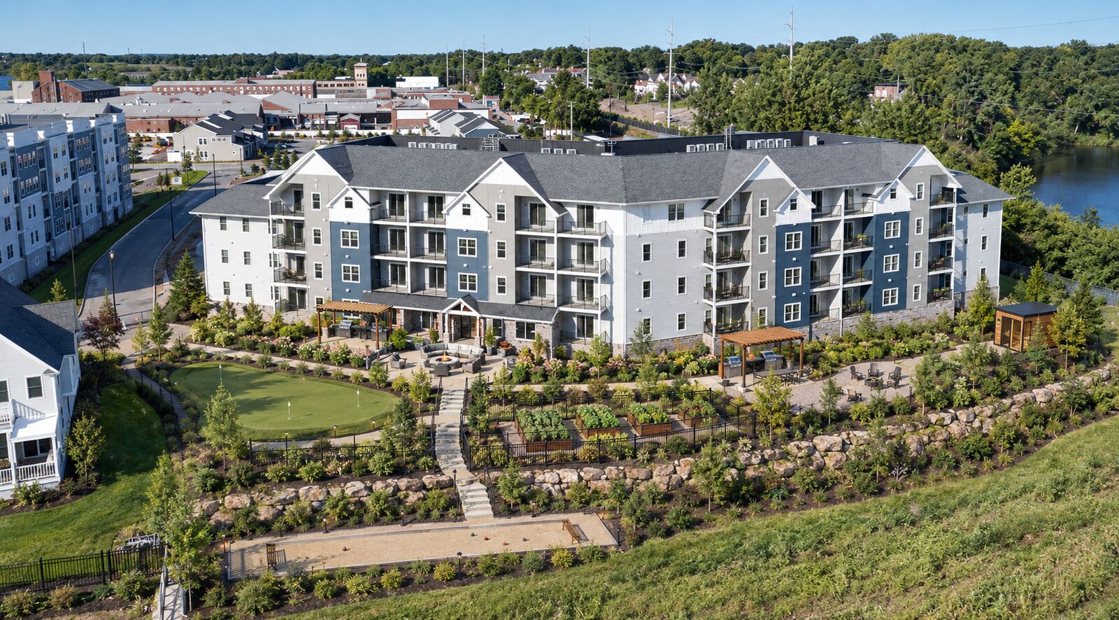The amenity courtyard at Building One — putting green, fire pit terrace, pergolas with grilling stations, sauna, raised garden beds and bocce court
